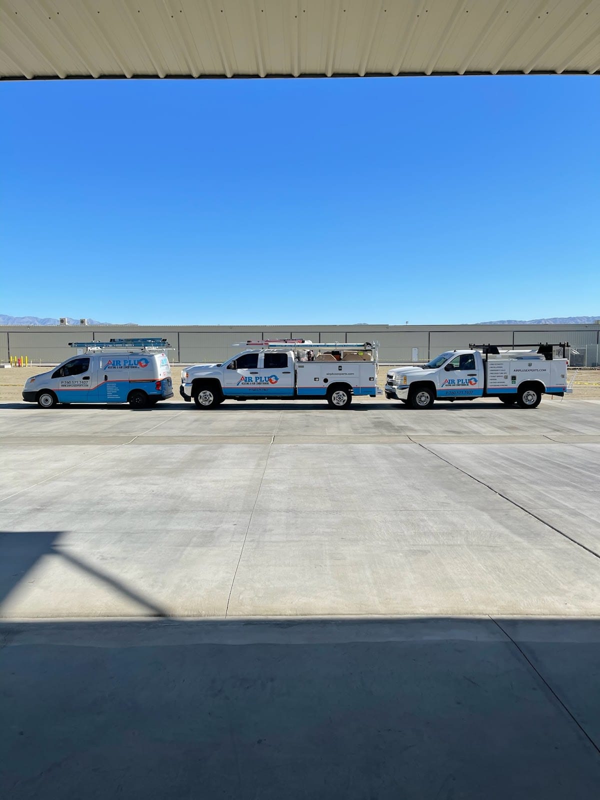 Fleet of Air Plus Heating & Cooling service vans and work trucks parked outside under a clear blue sky, ready for HVAC installation and repair.